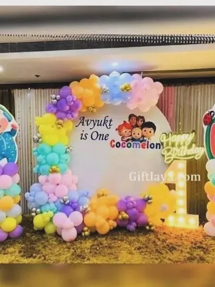 A vibrant Cocomelon theme for Avyukt's first birthday. This setup includes multiple character cutouts, a colorful balloon garland, and a light-up number "1".