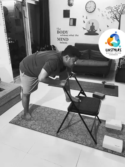 Using a chair for balance, a client works on a standing hip-opening stretch, improving mobility and flexibility.