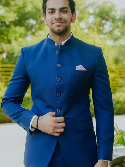 A smiling model in our royal blue Jodhpuri suit. We believe that a great outfit should not only look good but also make you feel happy and confident.