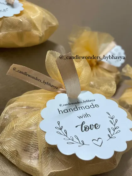 A simple yet elegant packaging option for favors, with the candle wrapped in a golden organza potli and a "handmade with love" tag.