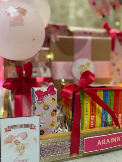 A close-up of the details, including a personalized birthday card and a set of 'My First Library' board books, perfect for a one-year-old.