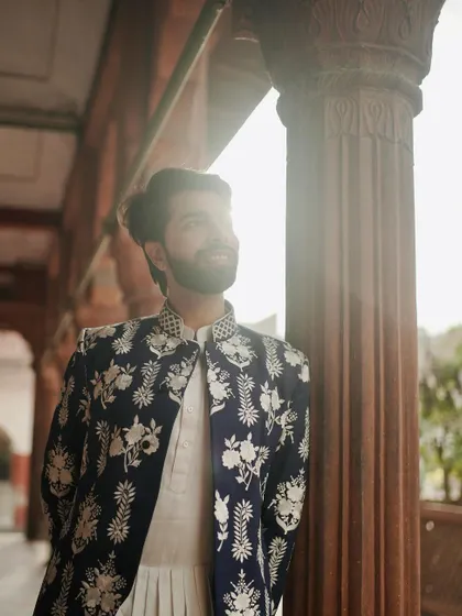 A sun-kissed shot highlighting the exquisite white floral embroidery on our navy Nehru jacket. It's a piece that feels both timeless and romantic.