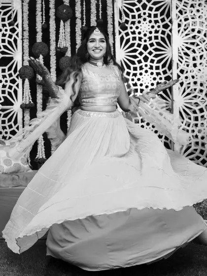 Fun and candid moments from a mehendi ceremony. The bride's makeup is fresh and playful, with a winged liner and glowing skin, perfect for celebrating with her loved ones. The hairstyle is a soft half-updo with pretty accessories.