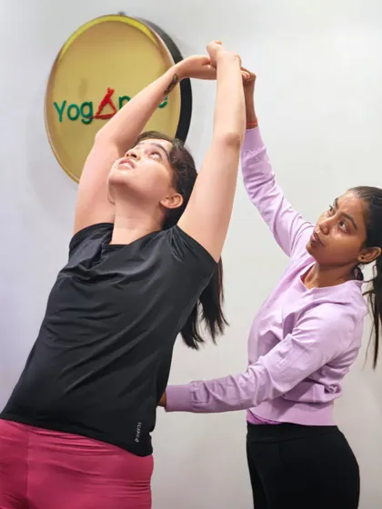 Personal guidance is a cornerstone of our teaching. Here, an instructor offers a gentle correction to help a student find more length and openness in her pose, ensuring she grows in her practice safely.