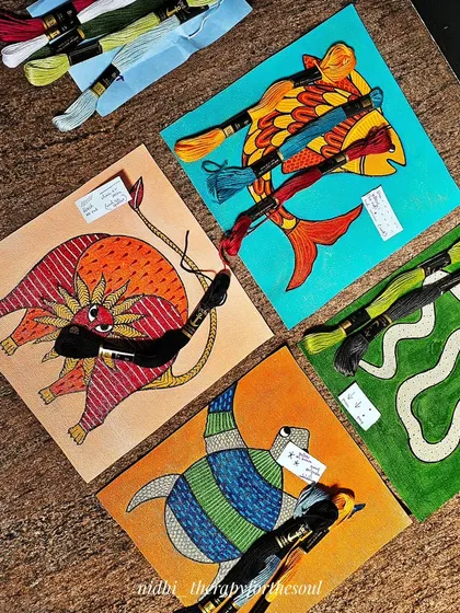 A behind-the-scenes look at the Gond art tile project. Here you can see the painted canvases with the threads chosen for the embroidery work, ready for my mom to work her magic.