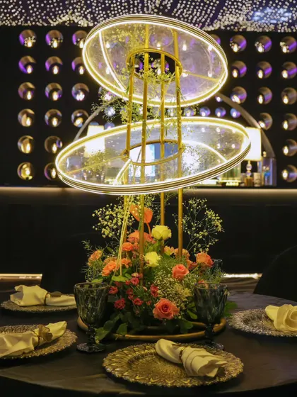 A futuristic and floral centerpiece. This custom light fixture with illuminated rings provides a modern contrast to the soft flower arrangement at its base.
