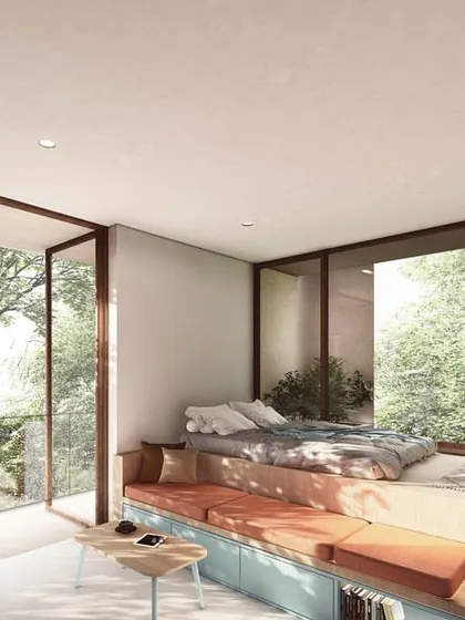 A compact studio apartment in The Nest, designed with modular, multi-functional furniture. The bed is raised on a platform with built-in storage and seating, maximizing space while maintaining a strong connection to the large window and outdoor view.