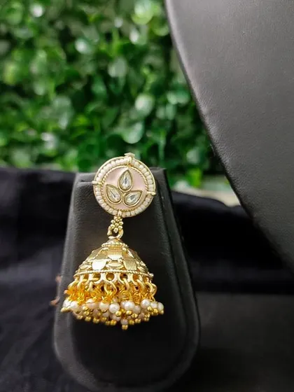 A modern jhumka with soft pink enamel work on a gold-tone base. This rental earring is perfect for a contemporary bride or for pre-wedding events.