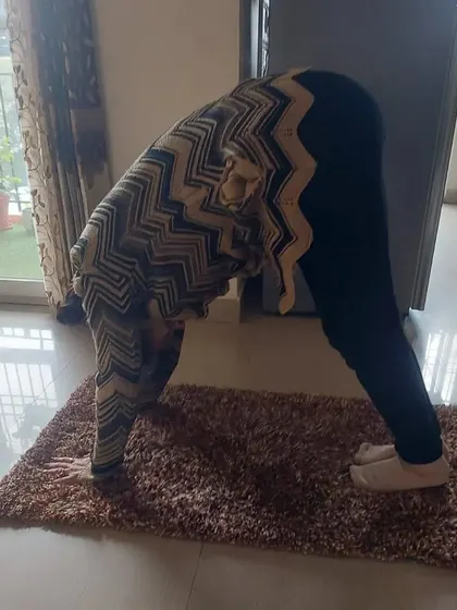 Age is no barrier to flexibility. This student is practicing a forward bend during a home visit session, showing great progress in her mobility.