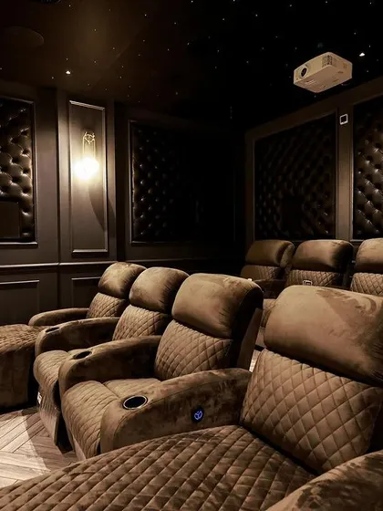 A different angle of the seating, showing the quilted pattern on the brown fabric recliners and the clean integration of the speakers into the wall panels.