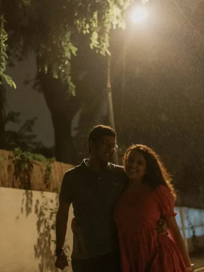 A couple walking together under a streetlight on a rainy night, creating a soft, romantic, and atmospheric portrait.
