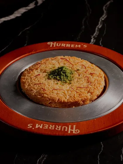 A beautifully plated Kunafah from Hurrem's Baklava. The lighting is carefully controlled to highlight the golden, crispy texture of the dessert, making it perfect for an online menu.