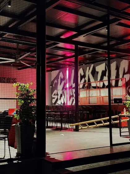 An exterior view looking into the restaurant, where the graffiti art is visible and illuminated by dramatic red lighting.