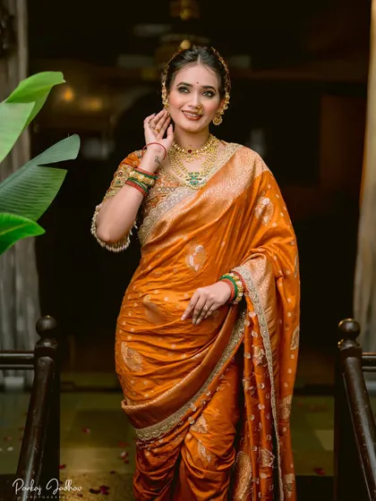 A happy bridal portrait, capturing the bride's smile and the rich colors of her orange saree and green bangles.