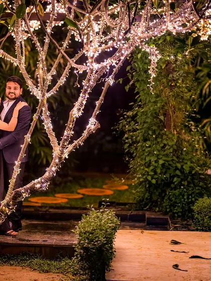 A quiet, intimate moment with the couple nestled by a tree wrapped in fairy lights. This composition creates a feeling of privacy and romance.