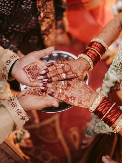 The joining of hands during a wedding ceremony, rich with the color of henna. This close-up shot highlights the cultural details and the symbolism of the union.