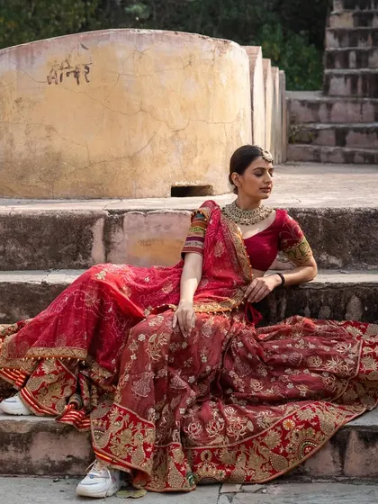 For the bride who loves tradition, we offer intricately detailed lehengas like this one from a top designer. The rich red fabric and exquisite embroidery create a timeless bridal look. You can get this high-end designer style for a fraction of the retail price.