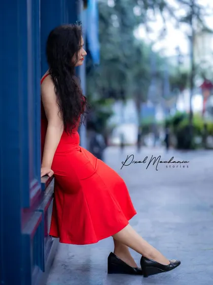 A quiet moment of reflection against a bold blue wall. This profile shot captures a different mood, showing versatility in posing and expression during our urban portrait sessions.