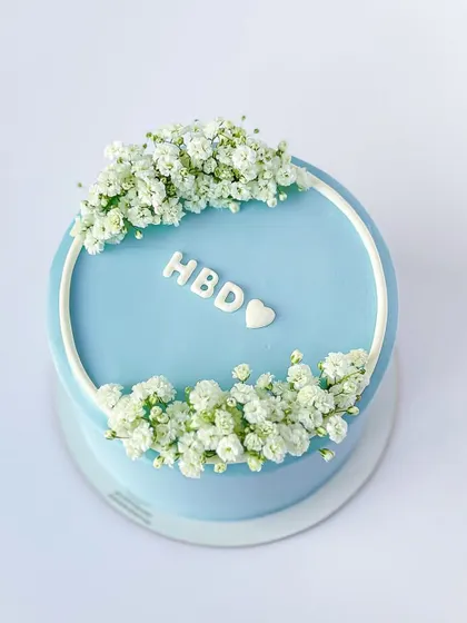 A minimalist "HBD" cake in a lovely pastel blue, adorned with a simple wreath of baby's breath. This shows that sometimes, less is more.