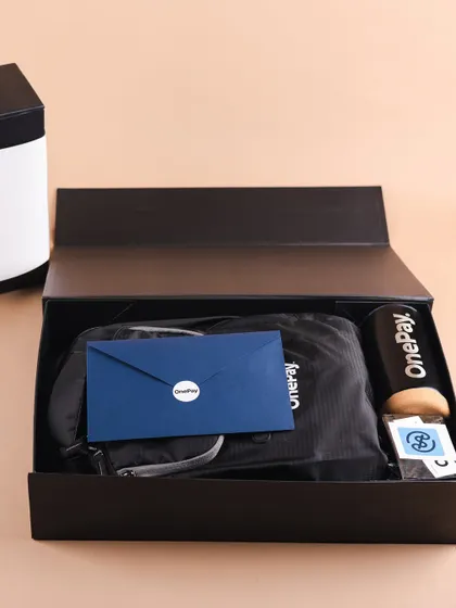 An inside look at the OnePay onboarding box. We carefully arrange each item, including the backpack, tumbler, and welcome envelope, to create a premium unboxing experience.