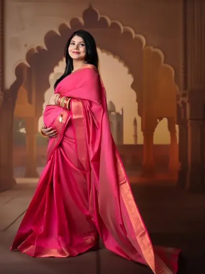 A beautiful profile shot against a warm, painterly backdrop. The mom-to-be's pose elegantly shows off her baby bump and the drape of her pink saree.