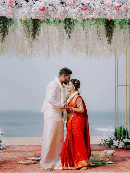 A tender forehead kiss under the mandap, with the ocean in the background. A perfect destination wedding moment.