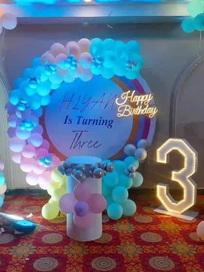 A sweet ice cream themed birthday party for a 3-year-old. The decoration includes a circular backdrop, large ice cream cone balloon sculptures, and a light-up number "3".