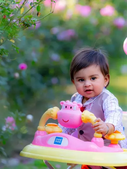 A baby enjoying the garden in a colorful walker. Outdoor sessions in locations like a rose garden provide a beautiful and natural setting for kids photography.