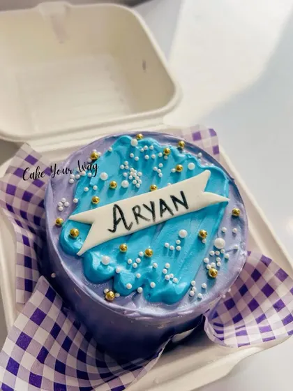 This personalized bento cake is packed in its signature takeaway box. The simple yet elegant design with a name banner, sprinkles, and a beautiful purple and blue color scheme makes it a perfect personal treat.