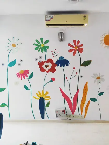 A bright and cheerful floral mural painted for a friend's new home. The vibrant, stylized flowers on a clean white wall add a splash of color and happiness to the living space.