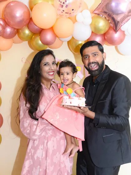 A fun and lively family photo from a first birthday party. The father's playful expression adds to the joyful atmosphere.