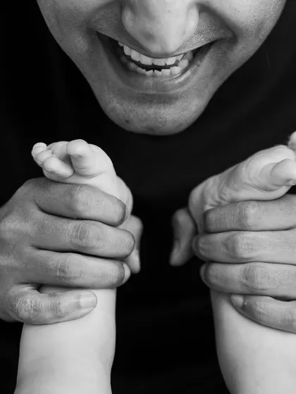 A father's smile and his baby's tiny feet. This unique angle in black and white creates an artistic and emotional portrait of their connection.