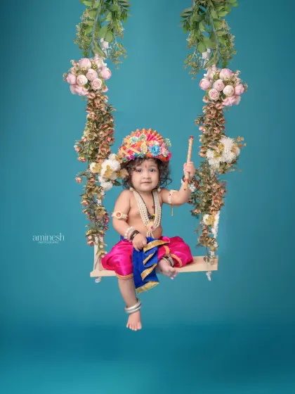 A simple yet beautiful portrait of baby Krishna on a floral swing against a solid blue background. This setup puts all the focus on your child's charming costume and expression.