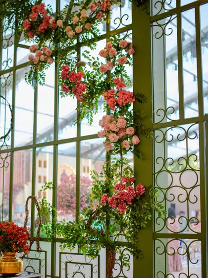 Floral arrangements climbing the green framework of the glasshouse, bringing the beauty of the garden indoors for the reception.