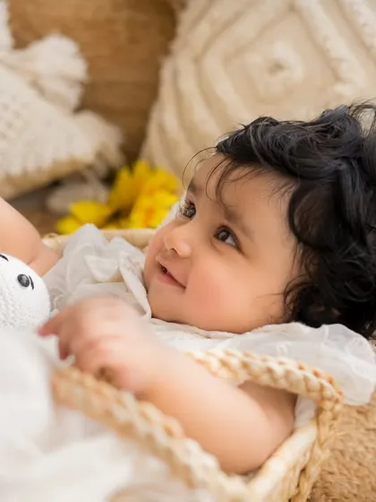 A sweet, upward glance from the baby girl in her basket. Milestone sessions are perfect for capturing new skills like sitting and smiling.