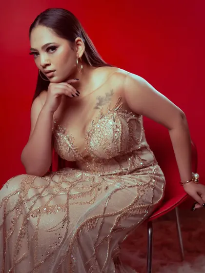 A seated pose in the champagne gold gown, showing off the illusion neckline and the intricate beadwork on the bodice.