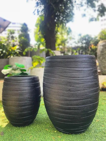 This pair of black FRP planters features a textured, brushed finish. They are highly durable, lightweight, and water-resistant.