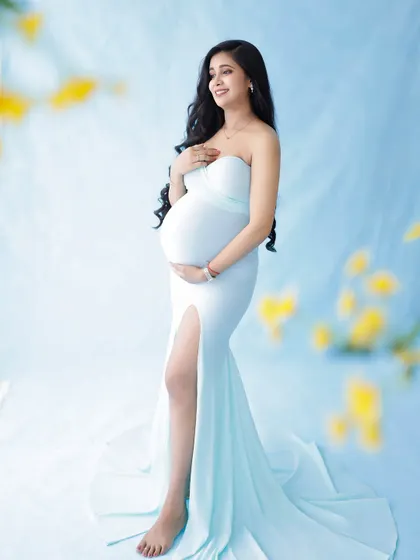 A serene and graceful portrait. The light blue gown and soft, dreamy background with yellow flowers create a peaceful and beautiful image.