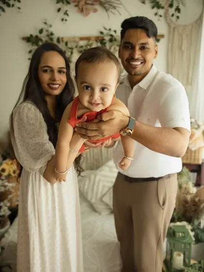 A playful and fun family portrait. The parents hold their baby up to the camera, capturing his adorable smile and creating a joyful, interactive memory.