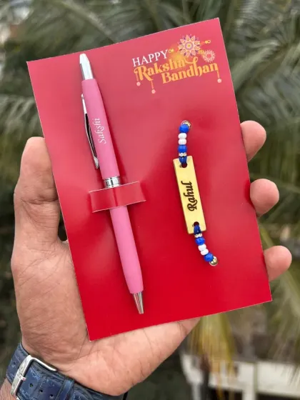 A simple and sweet Rakhi gift. This set includes a personalized turbo pen and a name-engraved rakhi, presented on a "Happy Raksha Bandhan" card. This one features the pen in pink.
