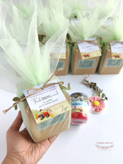 A farm-themed birthday party gift set, featuring a layered jar candle and a daisy wax sachet, all personalized for Zeyar's 2nd birthday.