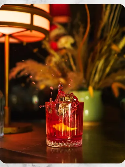 A classic Negroni captured in a moment of vibrant action. This image represents our dedication to perfecting timeless cocktails, focusing on quality ingredients and precise execution for a familiar yet elevated drinking experience.