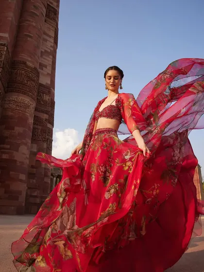 A dramatic, flowing red floral lehenga that is pure romance. The organza fabric is light and airy, creating beautiful movement, perfect for a bride who wants to make a statement.