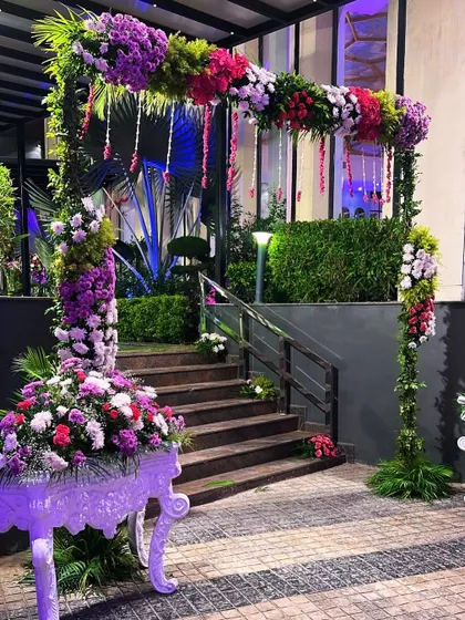 A beautiful floral entrance arch for an evening function. The structure is covered in purple and pink flowers, creating a vibrant welcome for guests.