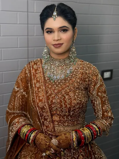A bride in a beautiful bronze-colored lehenga, with a statement diamond necklace.
