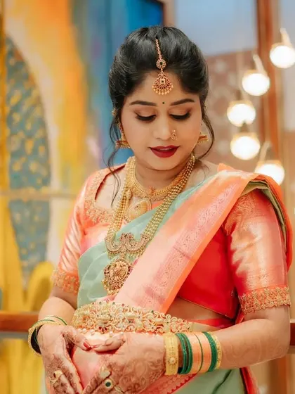 A close-up of Ranjitha's glowing baby shower look. The makeup is soft and traditional, with a beautiful red lip and defined eyes.