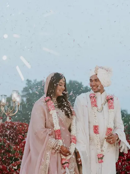 A candid moment of the couple, framed by a sea of red flowers and a shower of petals, capturing the happiness and love of the day.