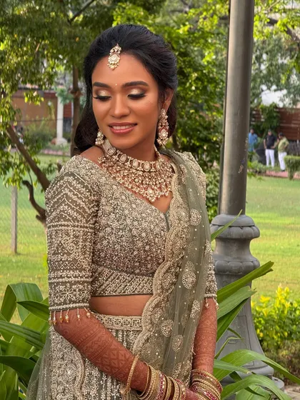 An outdoor portrait of Haritha. The natural light beautifully highlights her flawless makeup and the intricate details of her lehenga.