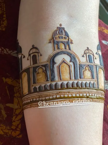 A close-up of a traditional dome or palace architecture motif. This element is a popular and beautiful way to start a bridal design at the elbow, creating a grand and regal look.