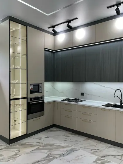 A corner view of the dual-tone kitchen, emphasizing the tall, glass-front display cabinet with interior lighting.